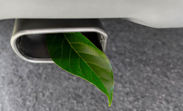 Auspuff mit grünem Blatt als Symbol für umweltfreundlichere Fahrzeuge.