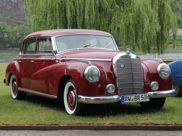 Ein roter Mercedes Benz W186-300 vor einem Baum auf der Wiese