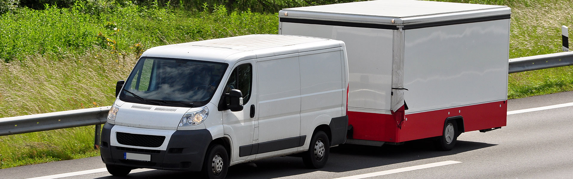 Beim Fahren mit Anhänger müssen Zuladung, Anhängelast und zulässiges Gesamtgewicht aufeinander abgestimmt sein Weißer Transporter mit geschlossenem Anhänger auf einer Straße