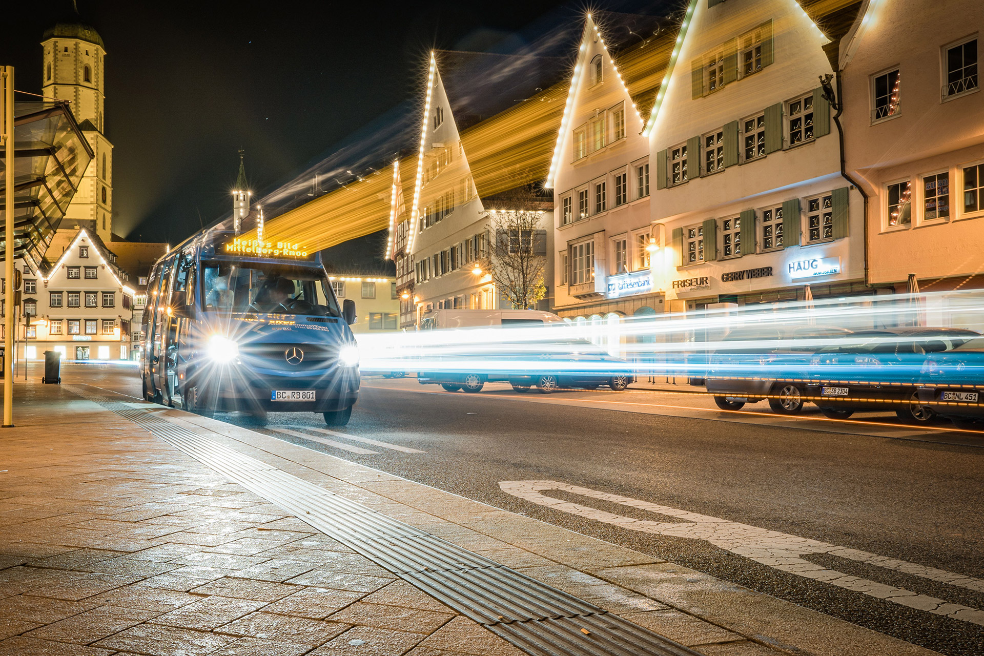 Transporter fährt nachts durch eine beleuchtete Innenstadt