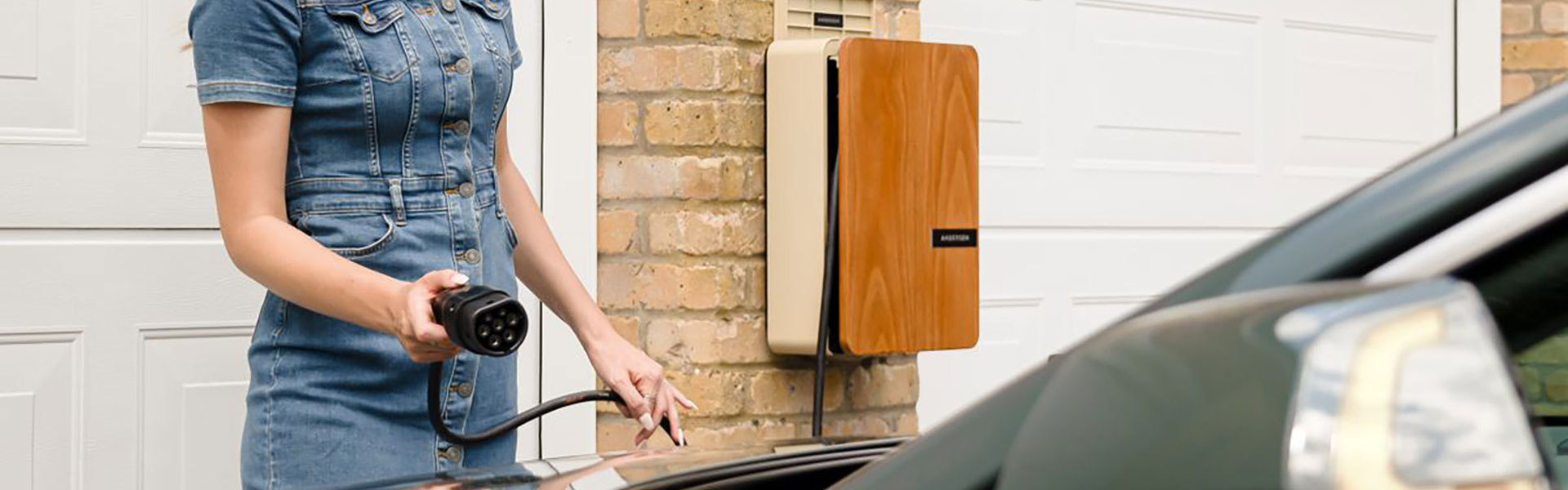 Eine Wallbox ist im Vergleich zur Haushaltssteckdose auf die höhere Belastung ausgelegt, die beim Laden des Batteriespeichers im E-Auto auftritt. Eine Frau steckt ihr E-Auto an einer Wallbox an