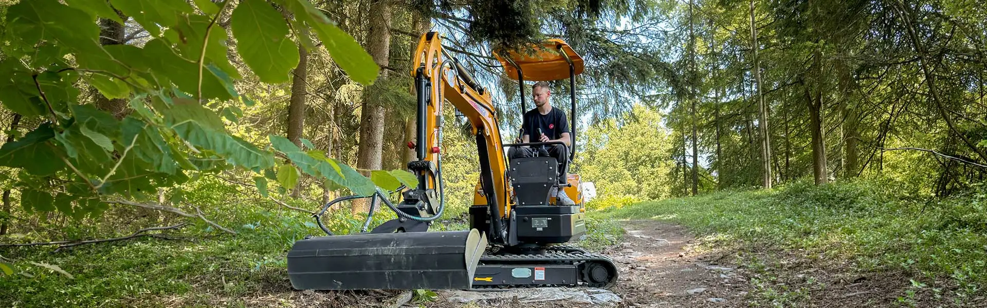 Rhinoceros Minibagger mit Knickarm und Humusschaufel bei Erdarbeiten im Wald