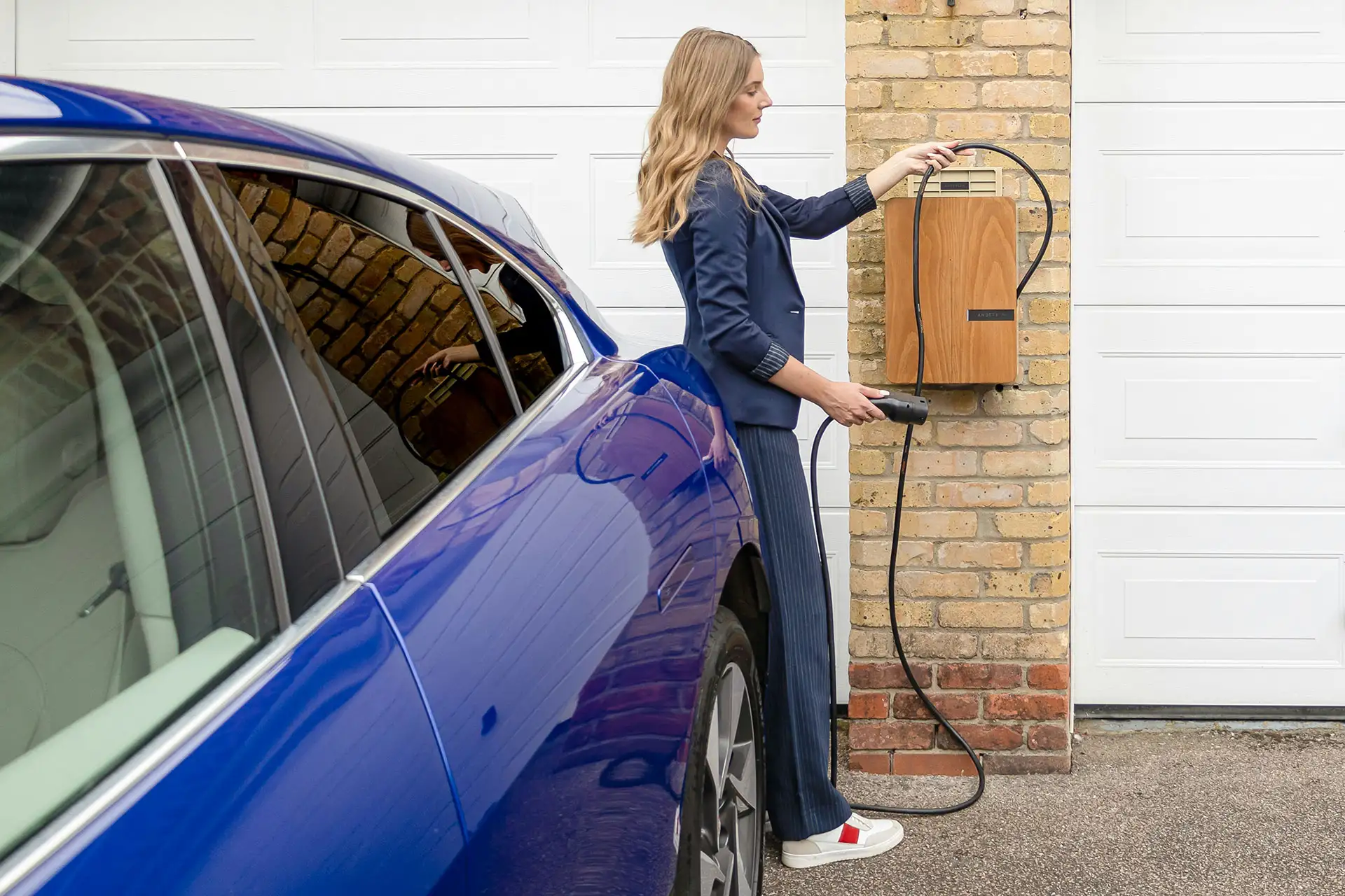 Eine Frau steckt ihr E-Auto an einer Wallbox an